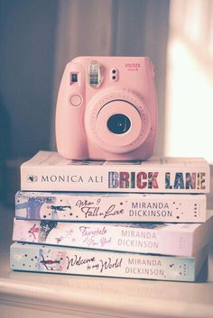 a pink camera sitting on top of three books