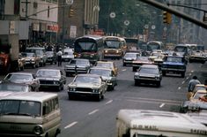 a busy city street filled with lots of traffic next to tall buildings on either side of the road