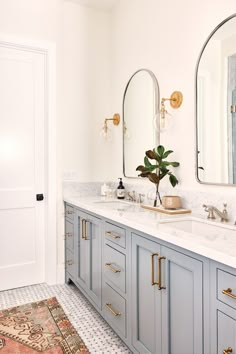 a bathroom with two sinks, mirrors and a rug on the floor in front of it