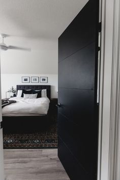 a bedroom with a large bed and black door leading to the other room that has a rug on the floor