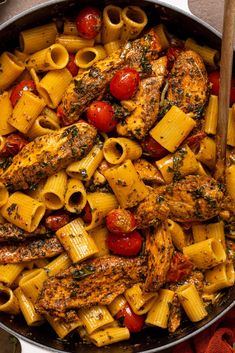 a skillet filled with chicken, pasta and tomatoes