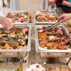 people are serving themselves food at a buffet