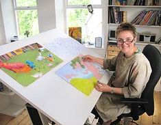 a woman sitting at a desk with some pictures on it