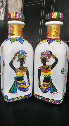 two bottles with designs painted on them sitting next to each other