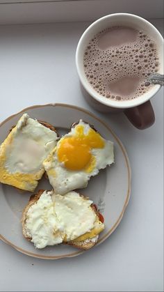 eggs and toast on a plate next to a cup of coffee