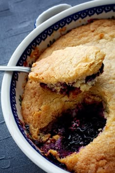 a blueberry cobbler in a white bowl with a serving utensil inside