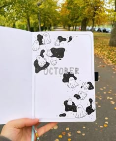 someone is holding up an open notebook with black and white drawings on it in the park