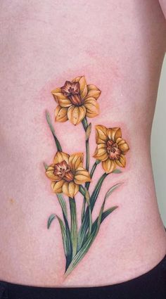 a woman's stomach with yellow flowers painted on the side by tattoo artist person