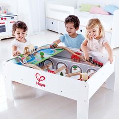 three children playing with a wooden train set in a play room at the same time