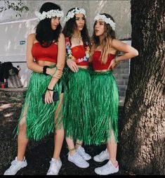 three women in grass skirts standing next to a tree