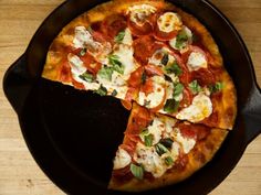 a pizza with cheese and herbs on it is cut into four slices, sitting on a plate