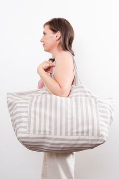 a woman carrying a gray and white striped tote bag with her hand on her shoulder