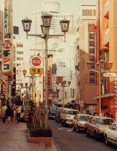 a city street filled with lots of cars and people walking on the side of it