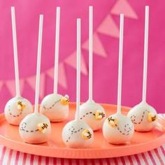 cake pops with white frosting and gold sprinkles on a pink plate