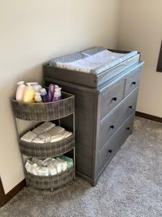 a baby crib next to a dresser with diapers on it