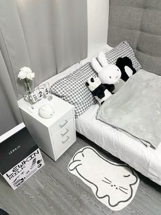 a white bed sitting next to a nightstand with a stuffed animal on top of it