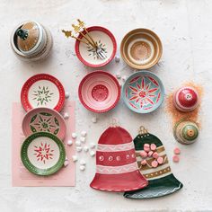 colorful dishes and plates are arranged on a white tablecloth with pink, green, red, and gold accents