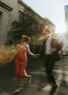 two people are running down the street with their hands in each other's pockets