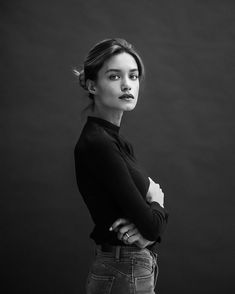 a black and white photo of a woman with her arms crossed looking at the camera