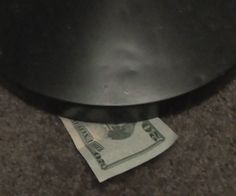 a stack of one hundred dollar bills sitting on top of a black trash can with the money sticking out of it