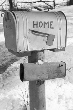 a mailbox with the word home written on it is in the snow next to a tree