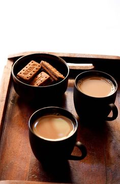 two cups of coffee and some crackers on a tray