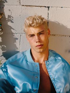 a young man with blonde hair wearing a blue jacket