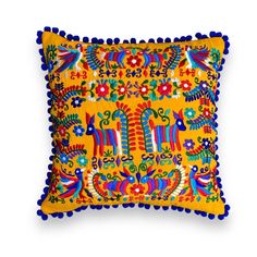 an embroidered pillow with pom poms on the front and sides, decorated in bright colors