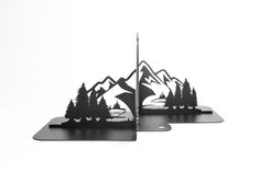 two metal bookends with mountains and trees in the middle on top of each other