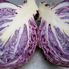 two purple cabbage halves cut in half on a cutting board