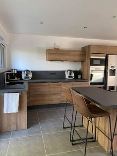 a modern kitchen with wooden cabinets and black counter tops, along with bar stools