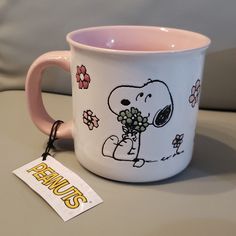 a pink and white coffee mug with a cartoon character holding flowers in its paws on a table