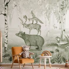 a child's room with an animal mural on the wall and a teddy bear sitting in a chair