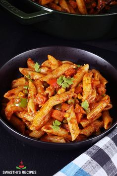 a bowl filled with pasta and sauce on top of a table next to a skillet