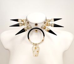 Embrace the allure of Tenebrous Divinity with our meticulously handcrafted Gothic Spike and Resin Ring Vinyl Choker.  - Each spike and resin ring is skillfully crafted by hand, adding a touch of bespoke artistry to this captivating piece.  - Made from high-quality transparent vinyl, this choker features edgy spikes and a mesmerizing resin ring, all meticulously handcrafted for a truly unique design. - The black base sets a dark and enchanting tone, complemented by transparent accents that add an intriguing touch.  - Golden glitter accents infuse the choker with a mystical radiance, while delicate gold foil details provide an exquisite finishing touch.  To enhance its mystique, the choker is accompanied by a coffin pendant, meticulously crafted with the same attention to detail. - Measuring Spiked Choker, Gothic Choker, Goth Choker, Gothic Chokers, Choker Collar Necklace, Concept Clothing, Golden Glitter, Heart Choker, Dog Jewelry