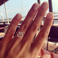 a close up of a person's hand with a diamond ring on their finger