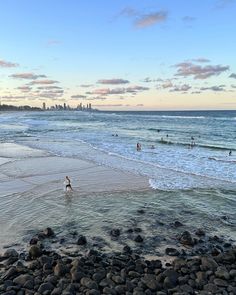 people are swimming in the ocean at sunset