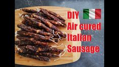 there is a wooden cutting board with sausages on it and an italian flag in the background