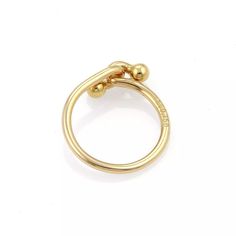 a gold ring with a knot on the middle and two small balls at the top