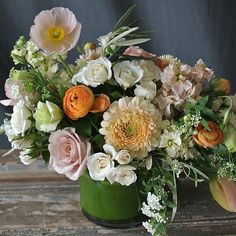 a green vase filled with lots of different colored flowers