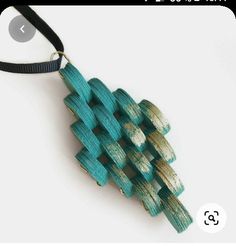 a necklace made out of wooden pieces on a black cord with gold and green accents