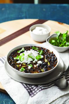 a bowl of black bean chili with sour cream and lettuce on the side