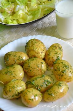 there are many potatoes on the plate next to a glass of milk and salad dressing