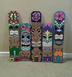 three wooden tiki masks are lined up in a row on the floor next to each other