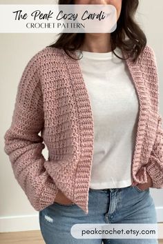 a woman standing in front of a wall wearing a pink cardigan