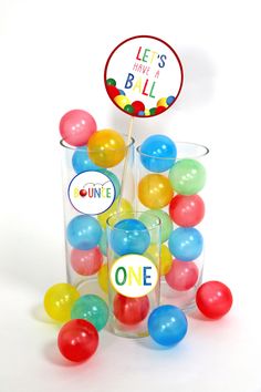 a glass filled with lots of colorful balloons next to a sign that says let's have a ball