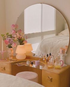 a mirror sitting on top of a dresser next to a table with flowers in it