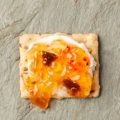 a cracker topped with fruit and cheese on top of a stone slabd surface