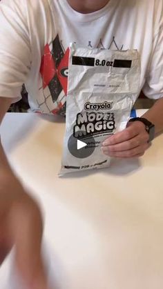 a man sitting at a table holding a bag of crayola pop magic