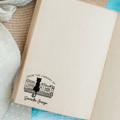 an open book sitting on top of a table next to a white bag and straw hat